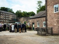 cr04  A members  in the mill yard, discussing what they have seen. The building on the left is a warehouse and the next one in the background is the first mill.