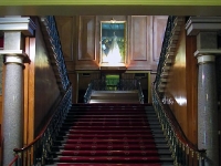 The Foyer Staircase.  This magnificent staircase goes up to the first floor from the foyer. At the top of the first flight of stairs is a portrait of the Queen above a very large plate glass mirror. The double second flight of stairs can be seen in the mirror. Looking closely at the portrait you can see the reflection of a chandelier in the glass.