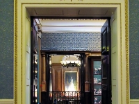 The Reception Room Doorway.  Looking through the drawing room doorway, across an adjacent room at the Queen's portrait on the stairs.
